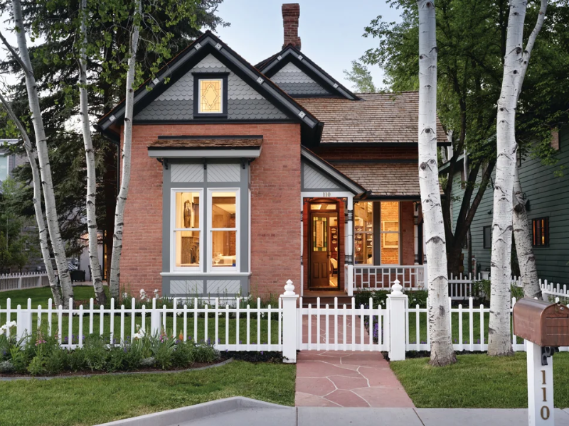 A small Victorian brick house with a white picket fence in Aspen CO