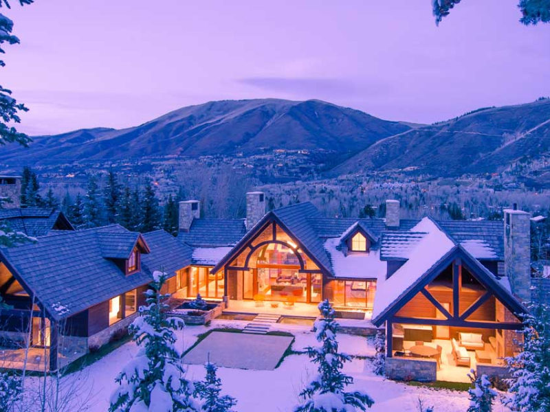 A large house in the Aspen snow with mountains in the background