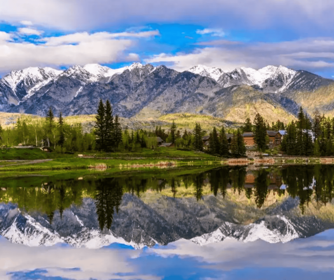 A lake with mountains in the background and trees on the shore.