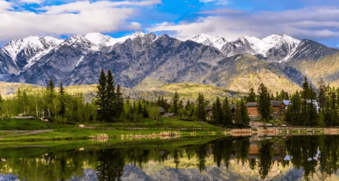 A lake with mountains in the background and trees on the shore.