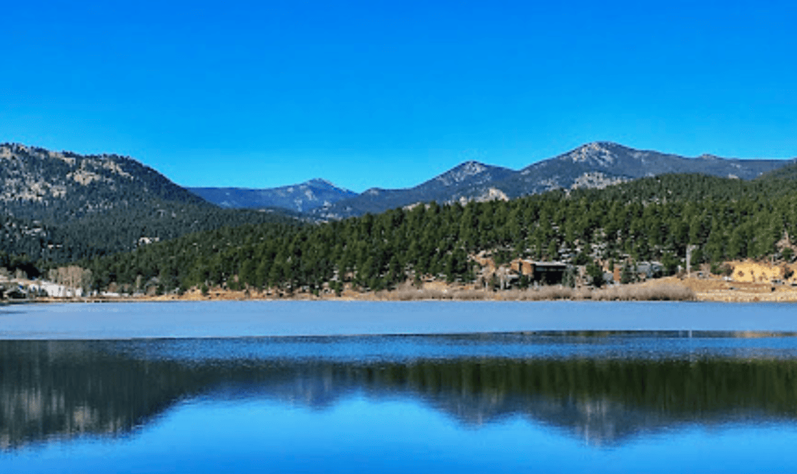 A lake with mountains in the background and trees on the shore.