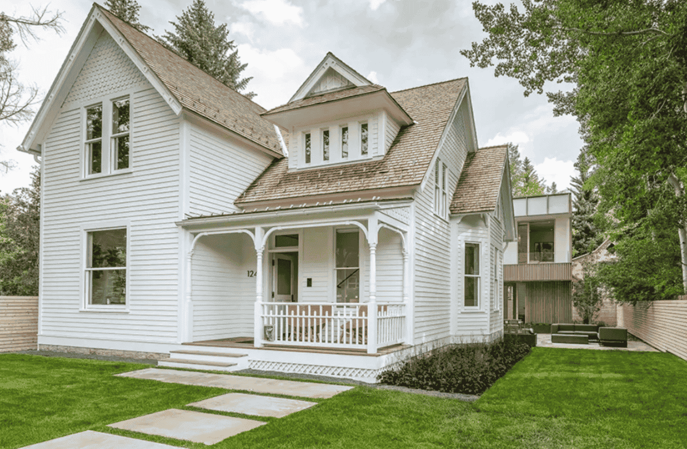 A white house with a porch and a walkway in front of it.