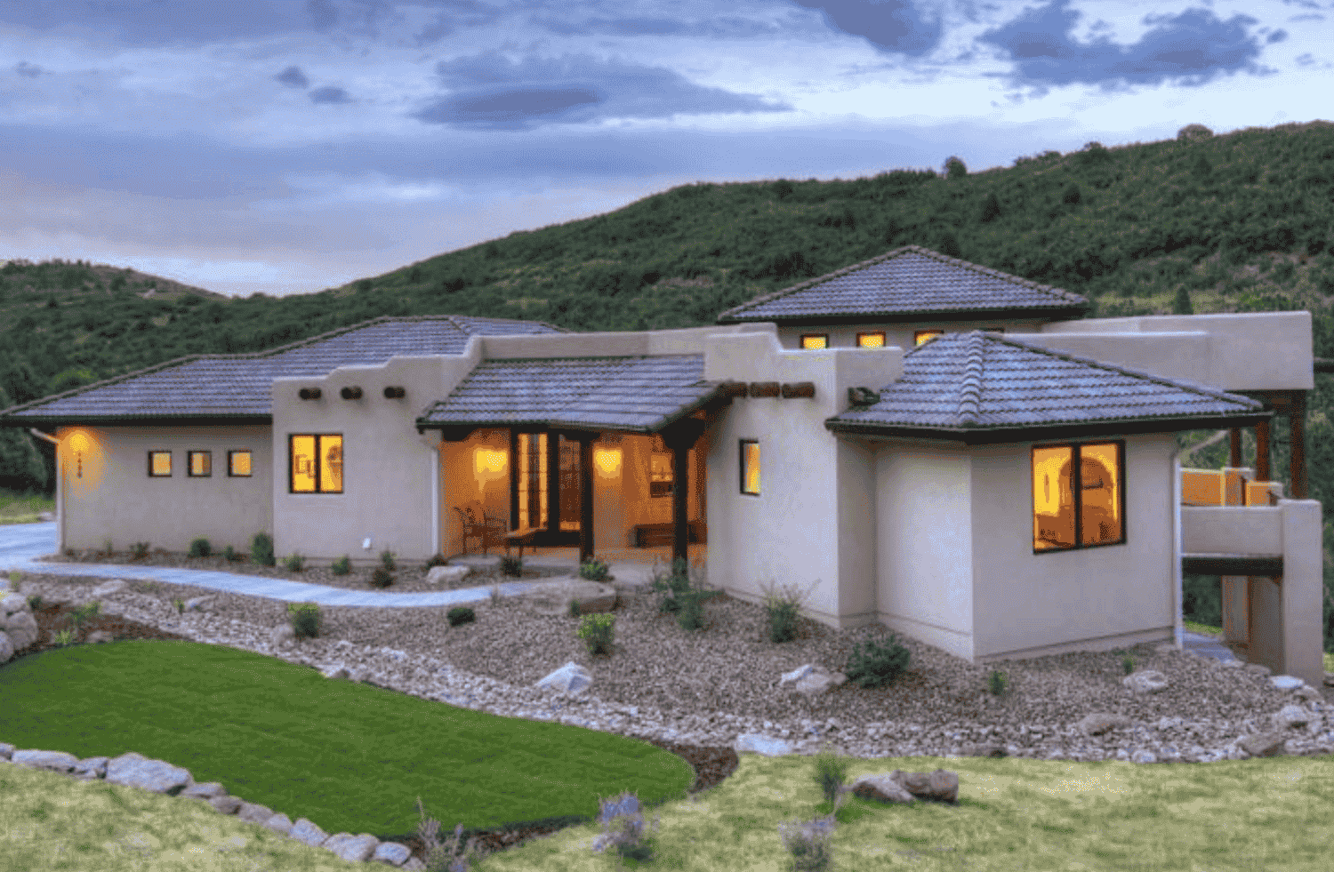 A large house is sitting on top of a lush green hillside.