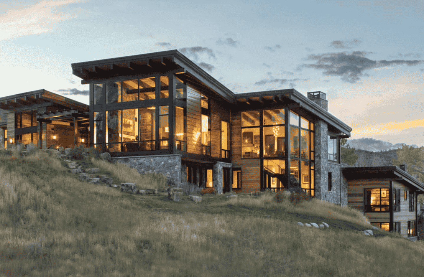 A large house with a lot of windows is sitting on top of a hill.