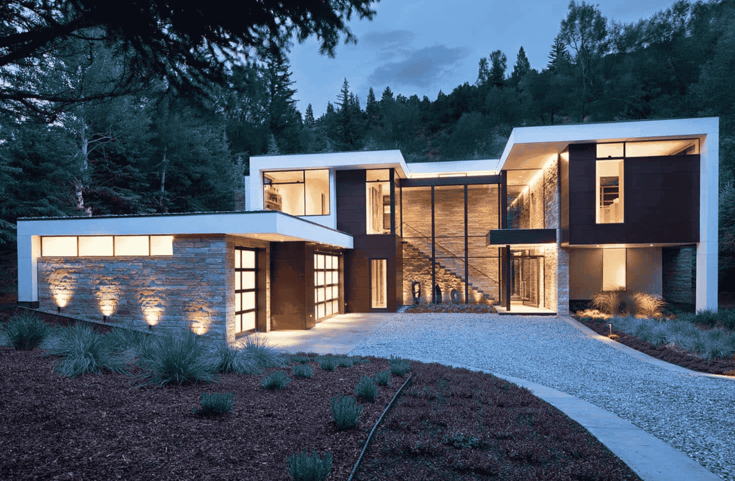 A modern house with a lot of windows is lit up at night.