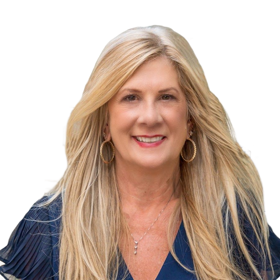 A smiling person with shoulder-length hair and a beard, wearing a blue textured blazer and a white collared shirt.