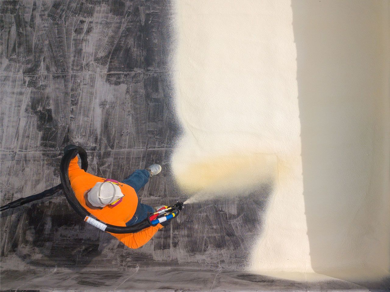 A man is spraying foam on a wall.