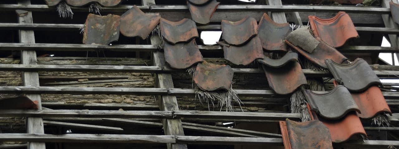 A bunch of roof tiles are hanging from a wooden structure.