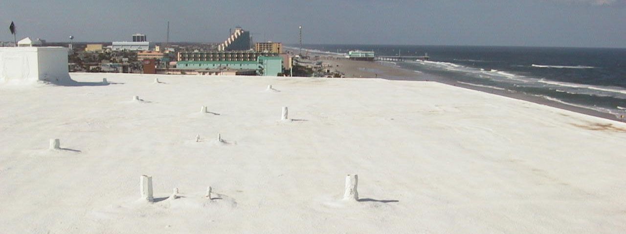A white roof with a view of the ocean and a city in the background.