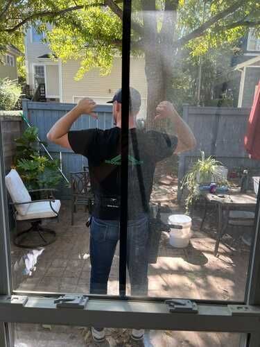 A man is standing in front of a window cleaning it.
