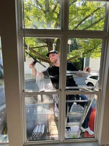 A man is cleaning a window with a squeegee.