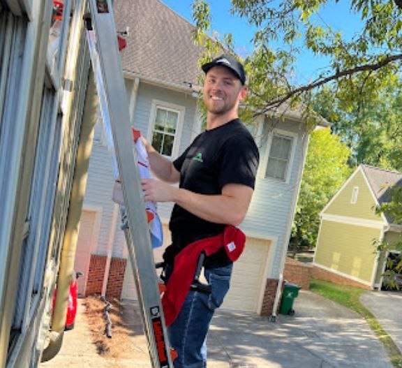 A man is standing on a ladder in front of a house.