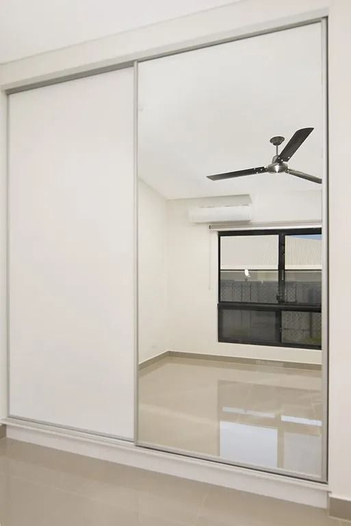 An empty room with a ceiling fan and a large mirror on the wall — Precision Shower Screens & Wardrobes In Yarrawonga, NT