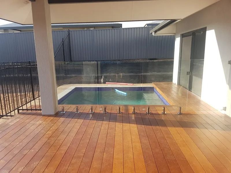 A wooden deck with a swimming pool in the background — Precision Shower Screens & Wardrobes In Yarrawonga, NT