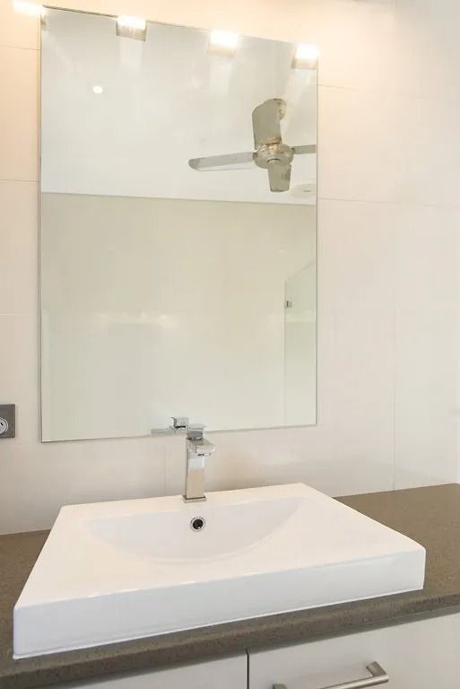 A bathroom with a sink , mirror and ceiling fan — Precision Shower Screens & Wardrobes In Yarrawonga, NT