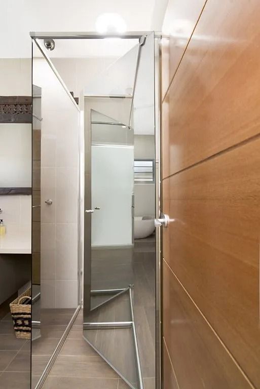 A bathroom with a walk in shower and a wooden door — Precision Shower Screens & Wardrobes In Yarrawonga, NT