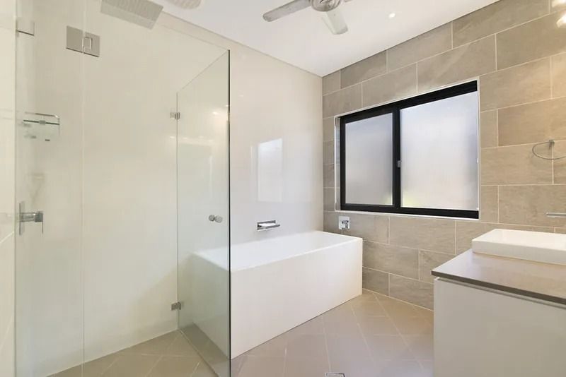A bathroom with a bathtub , sink , shower and window — Precision Shower Screens & Wardrobes In Yarrawonga, NT