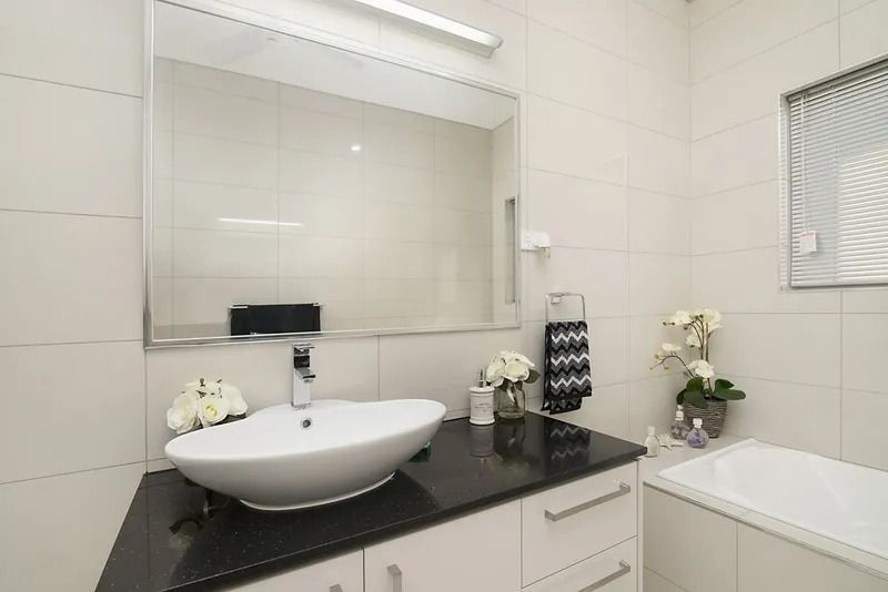 A bathroom with a sink , mirror and bathtub — Precision Shower Screens & Wardrobes In Yarrawonga, NT