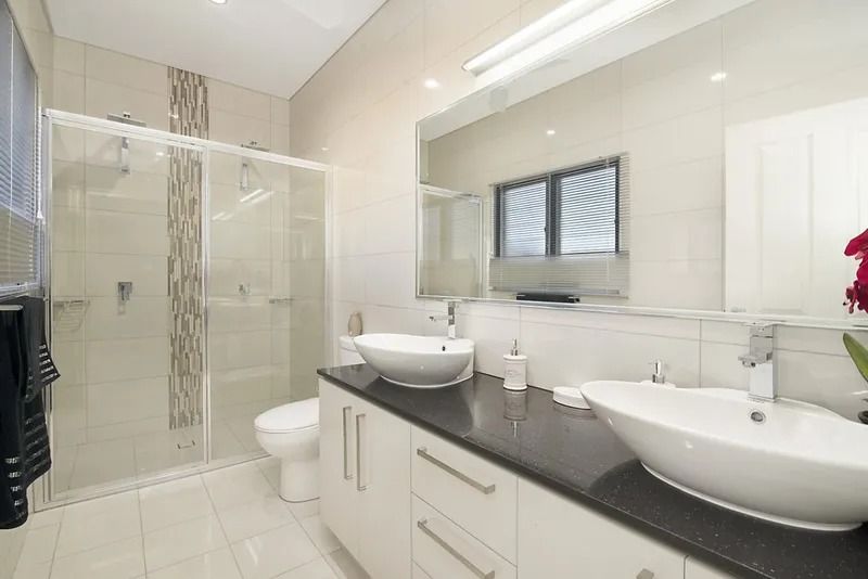 A bathroom with two sinks , a toilet and a shower — Precision Shower Screens & Wardrobes In Yarrawonga, NT
