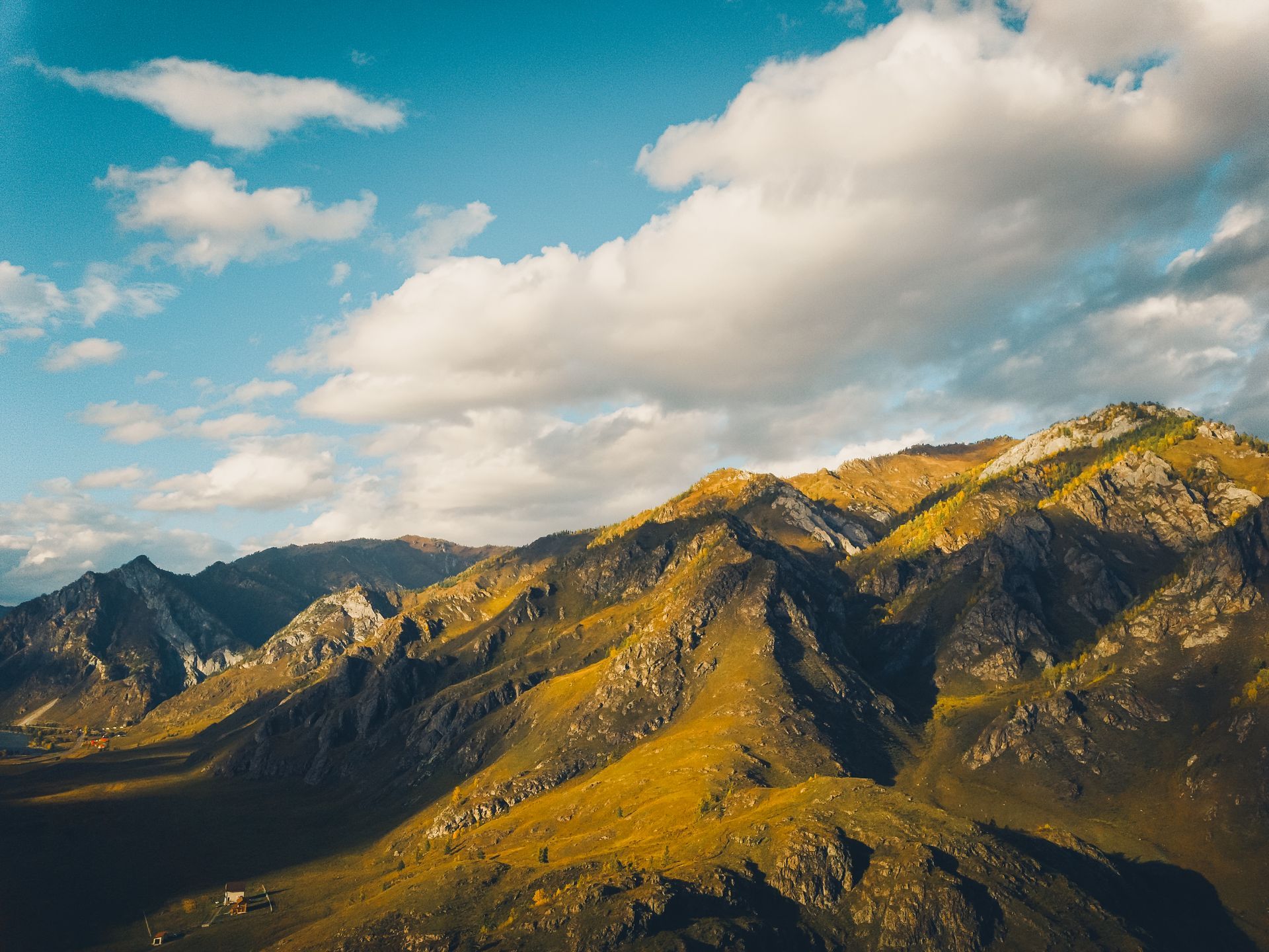 An aerial view of a mountain range with clouds in the sky.
