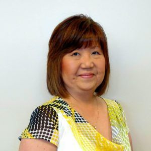 A woman wearing a yellow and black shirt is smiling for the camera.