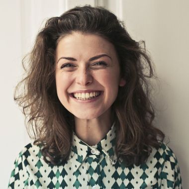 A woman wearing a green and white checkered shirt is smiling