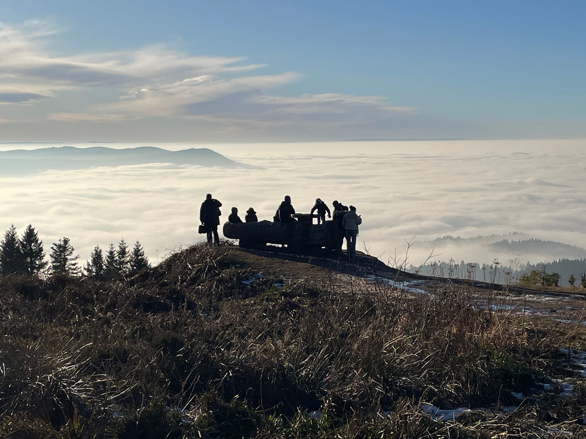 Eine Gruppe von Menschen steht auf einem Hügel und blickt auf ein auf einen Wolkensee ( Tal gefüllt mit Wolken / Nebel) 