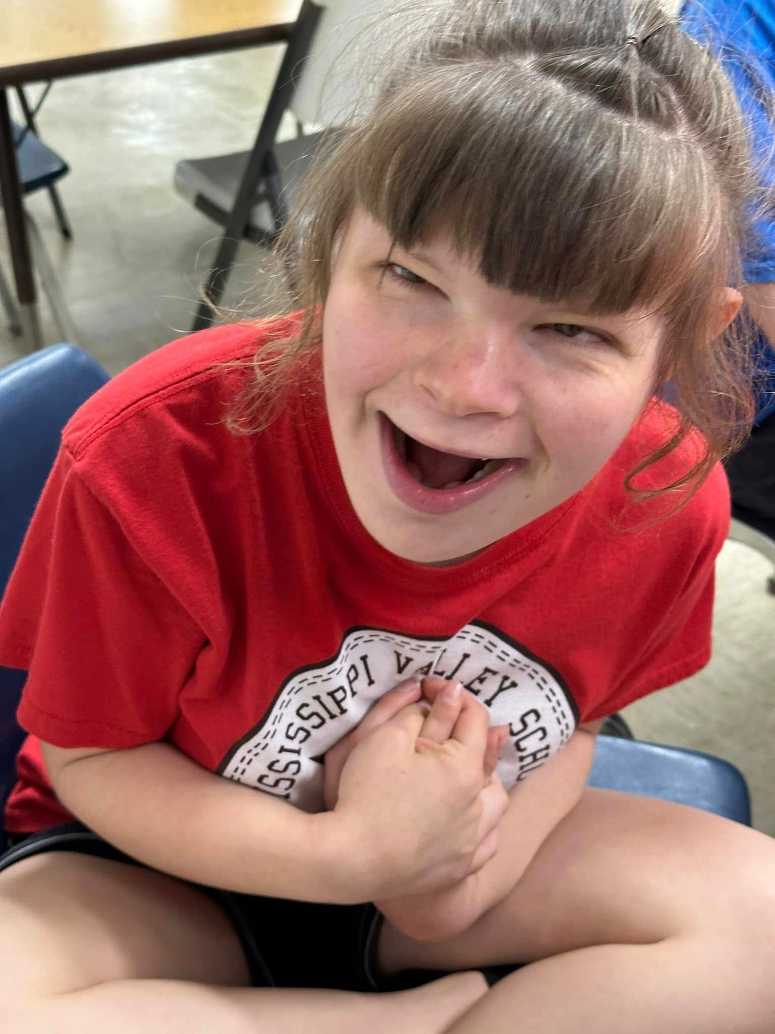 A young woman in a red shirt with the logo 