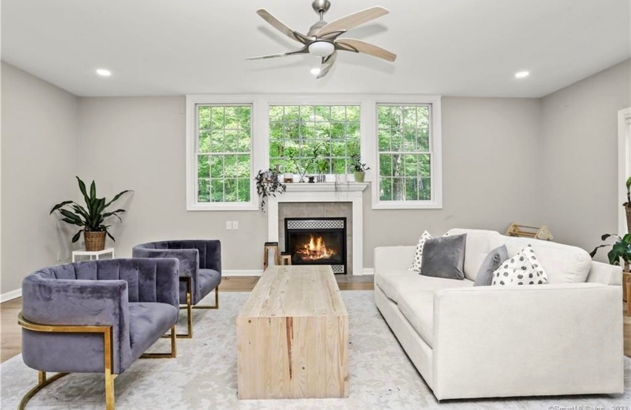 A living room with a fireplace and a ceiling fan