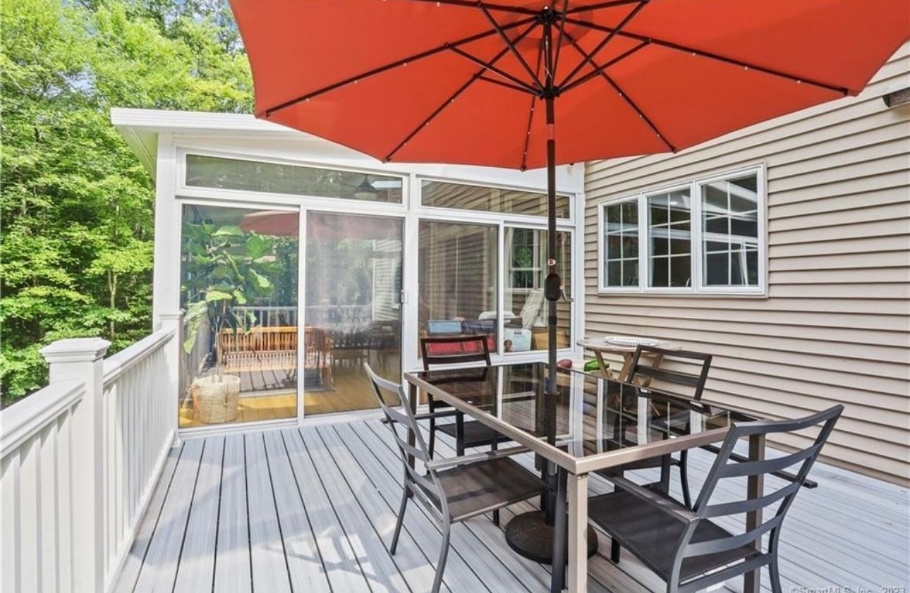 A deck with a table and chairs and an umbrella.