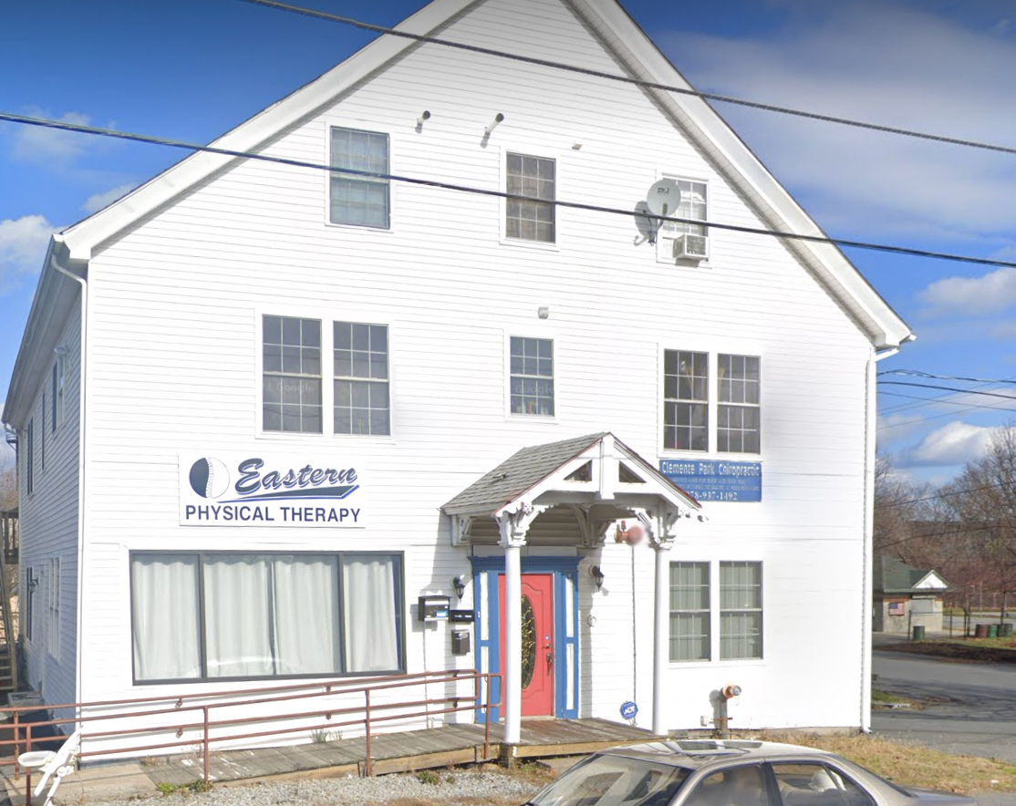 A white building with a car parked in front of it.