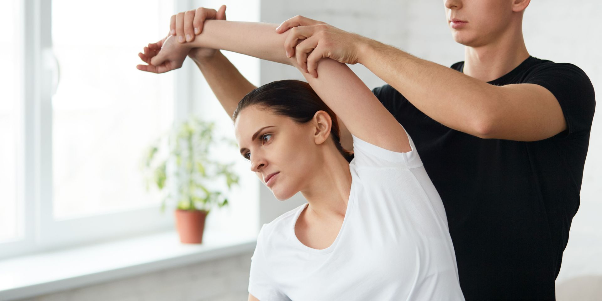 A man is helping a woman stretch her arms.