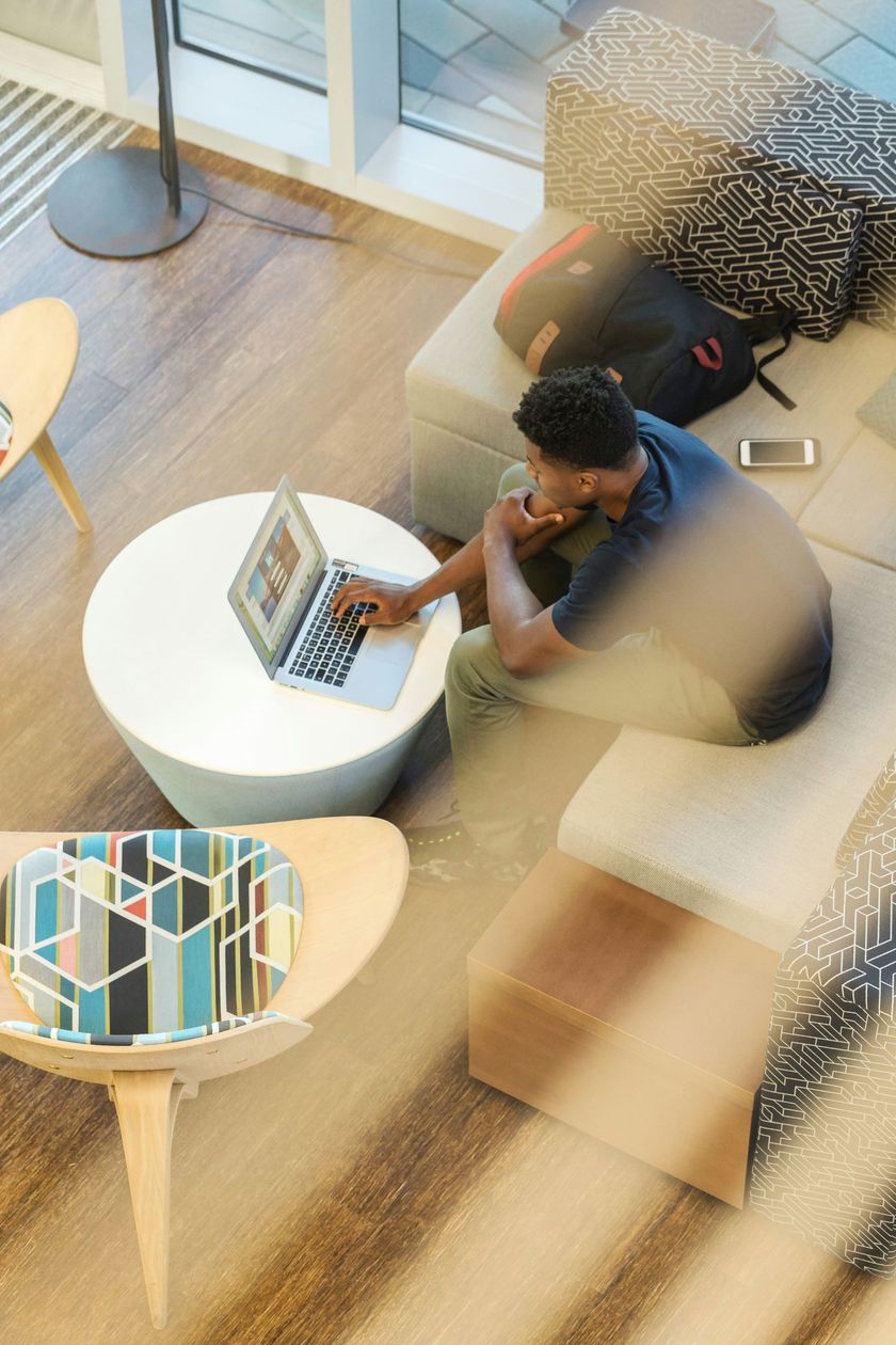 A man is sitting on a couch using a laptop computer.