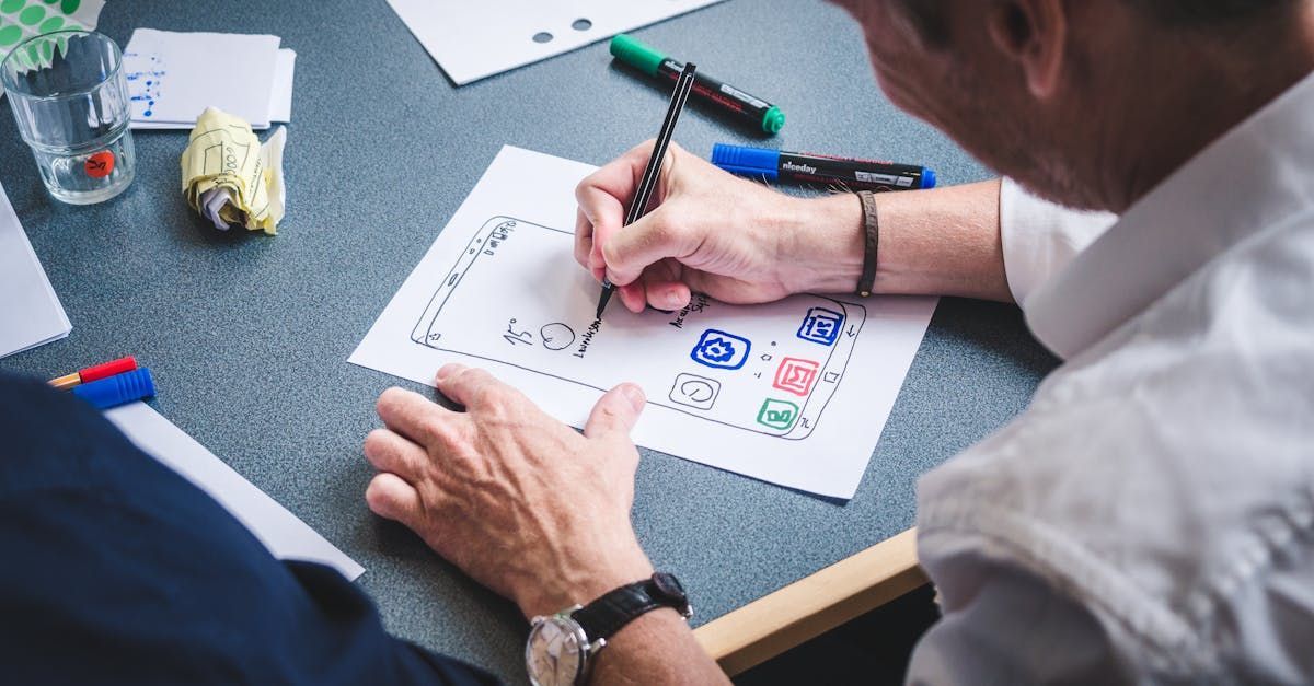 A man and a woman are sitting at a table drawing on a piece of paper.