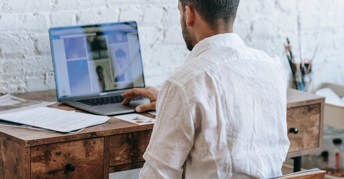 A man is sitting at a desk using a laptop computer.