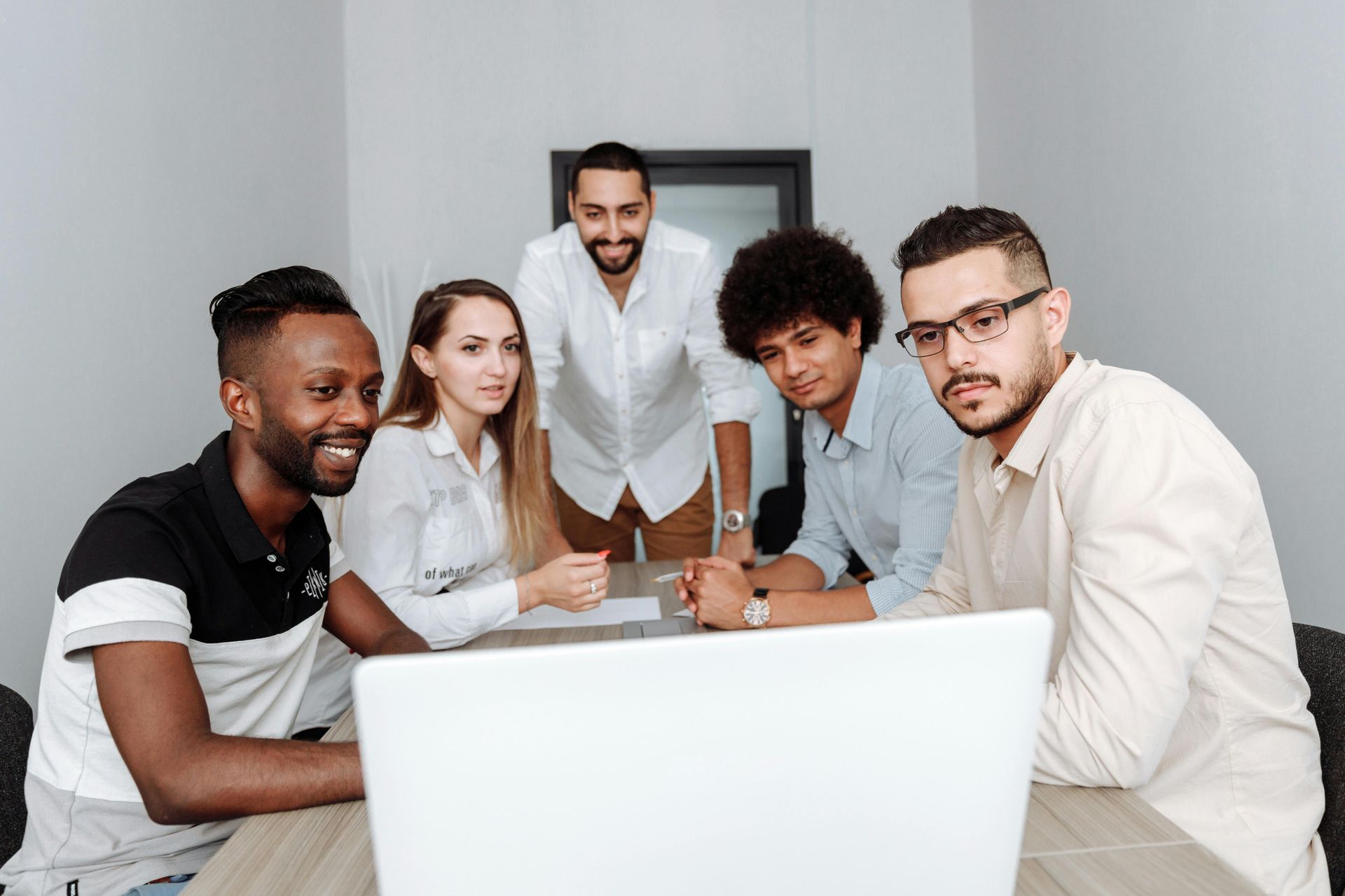 Group of people looking at a laptop, indoors. Diverse team at a table, focused and engaged.