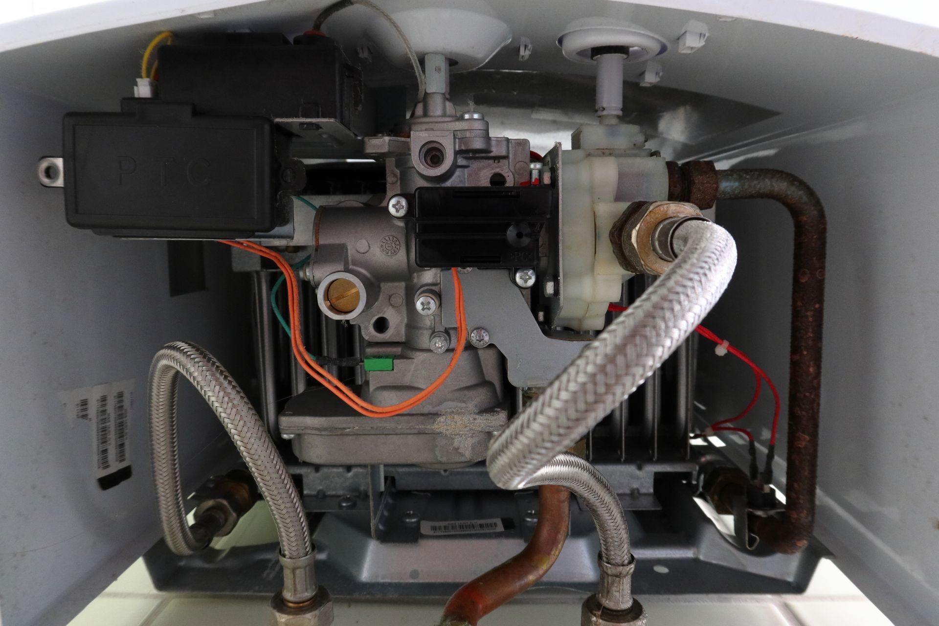 Close-up of exposed furnace interior with wiring, pipes, and mechanical components inside a metal cabinet