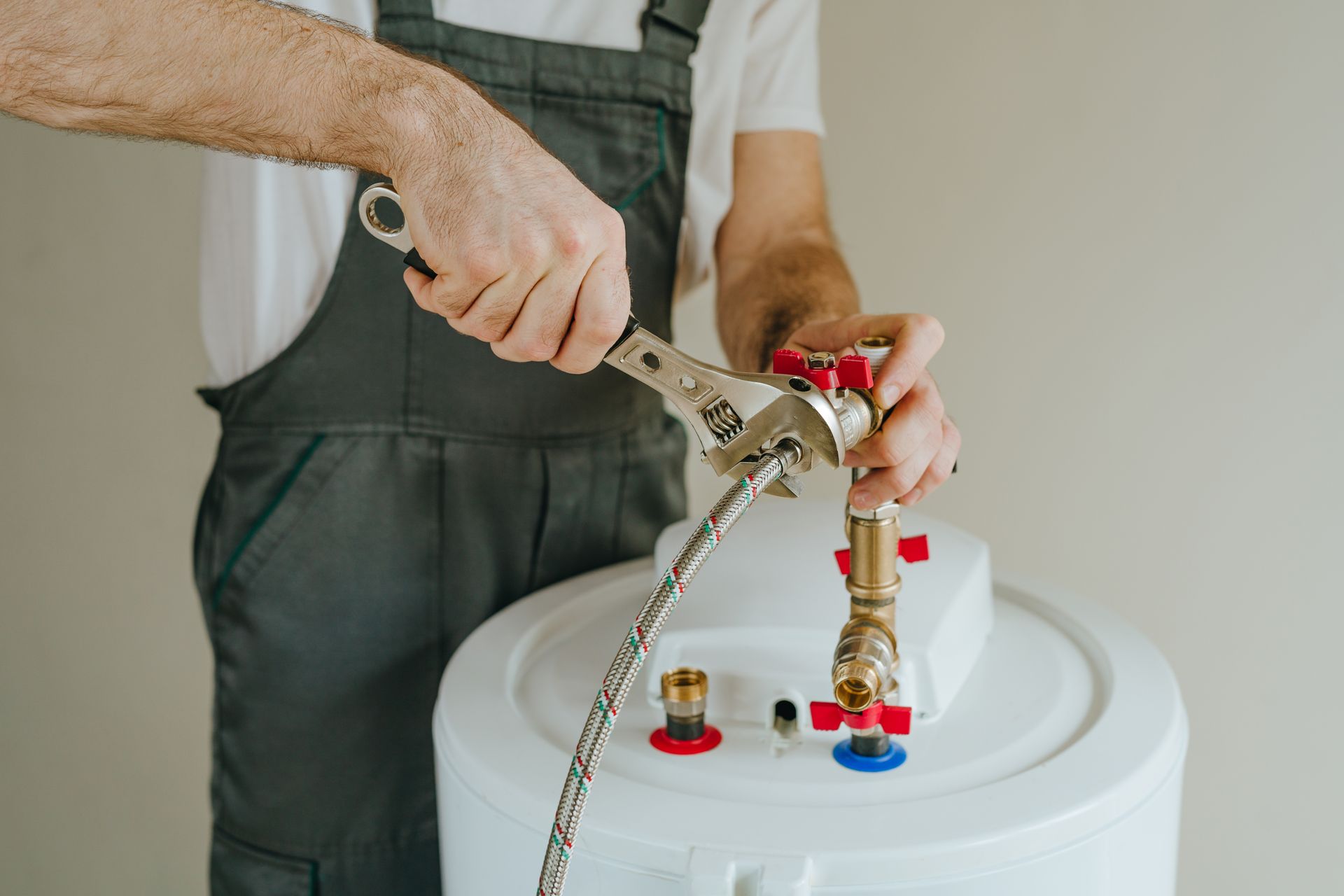 Person tightening a valve on a white water heater with a wrench