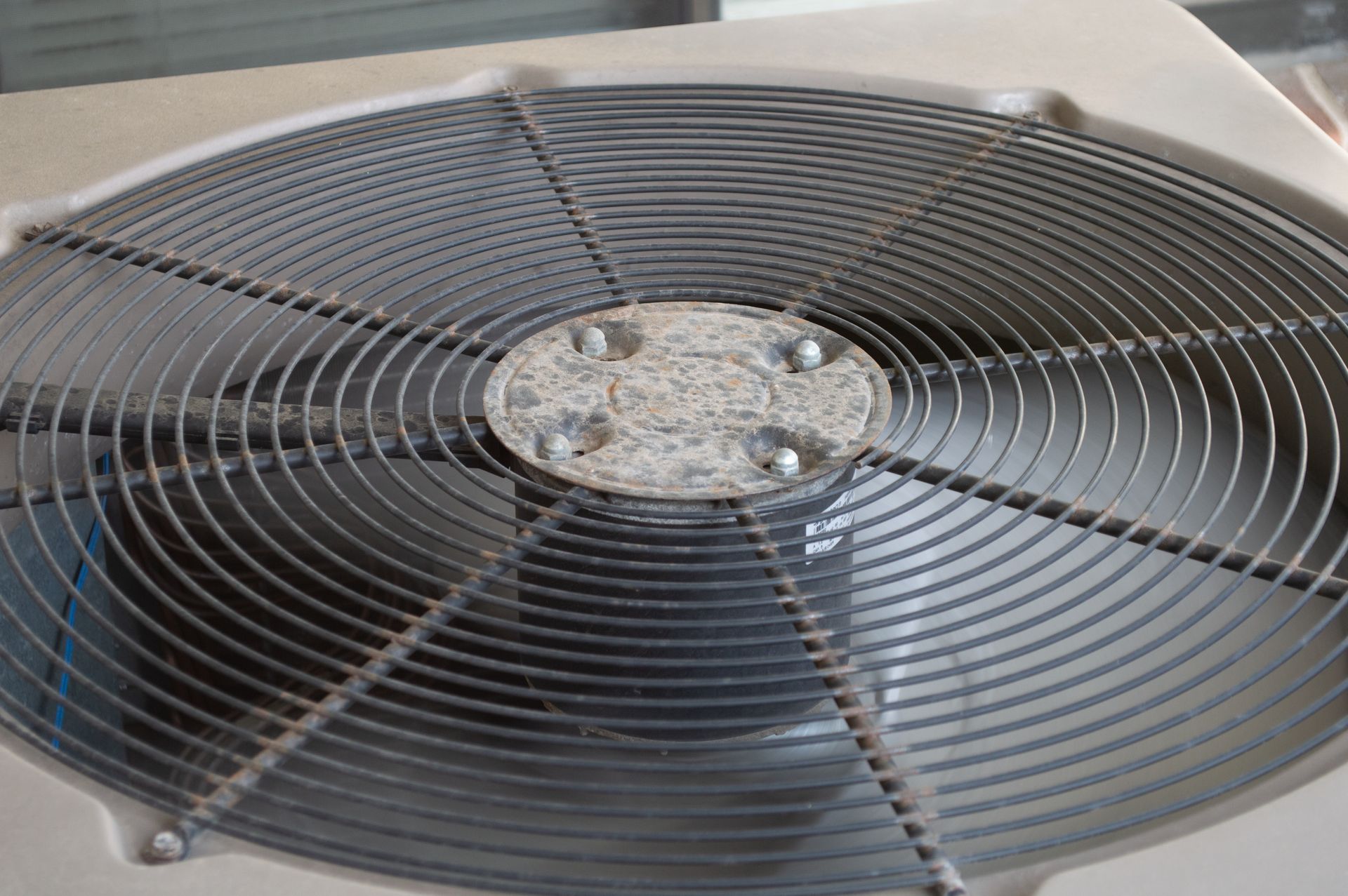 Top view of a large outdoor HVAC fan unit with a circular metal grille.