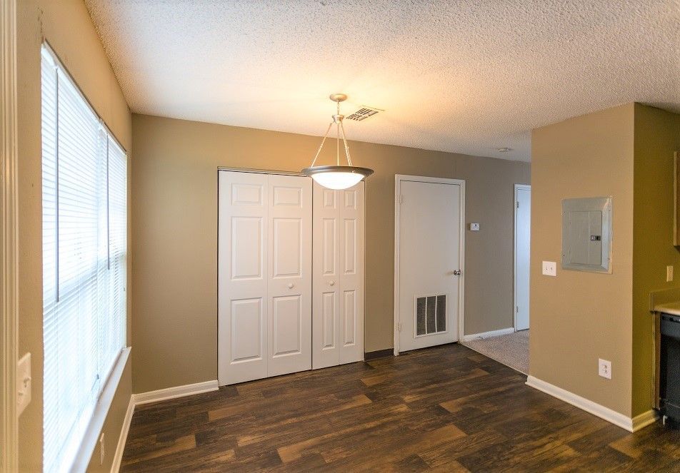 A brightly lit room with brown walls, dark wood-look floors, a white sliding closet, and a contemporary ceiling light.