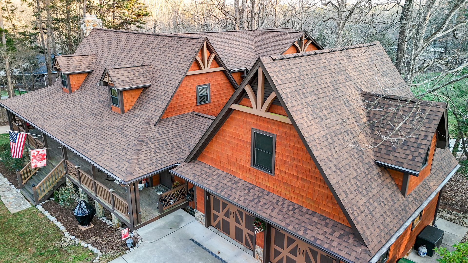 Brown and orange multi-gabled house with dormers and garage, surrounded by trees.
