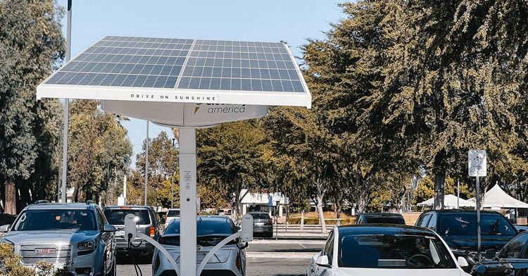 A parking lot with cars parked under a solar panel.