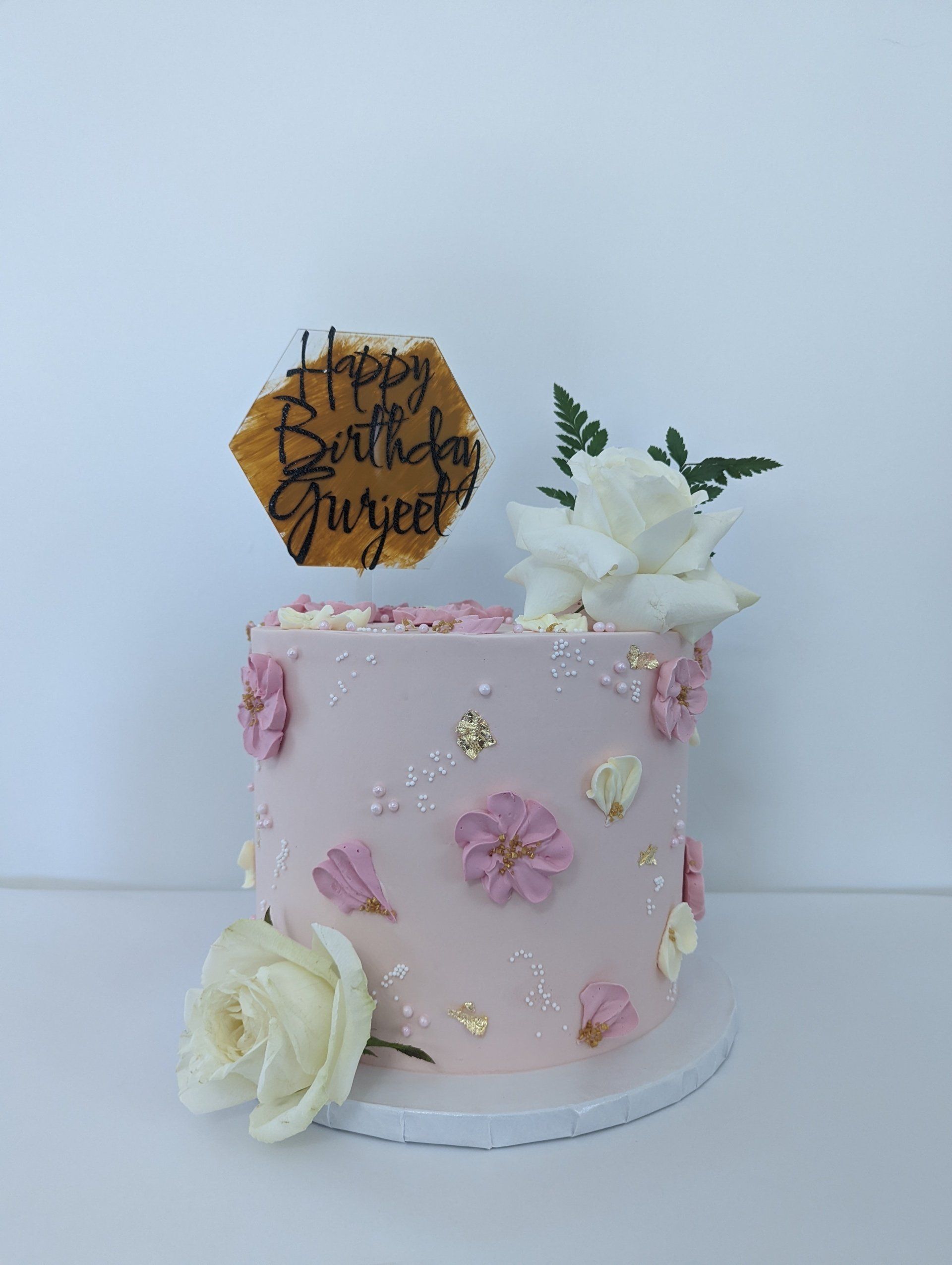 pink cake with florals and a topper