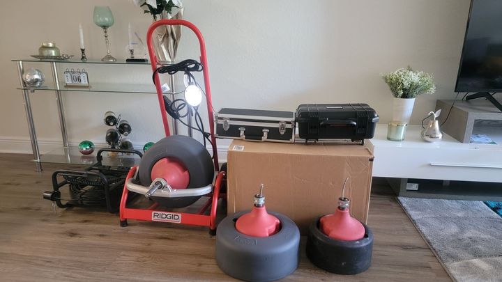Living room with exercise equipment, including a red floor machine, weights, and two air-filled training dummies.