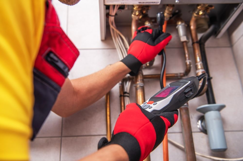 Technician using a wrench to work on copper pipes under a sink