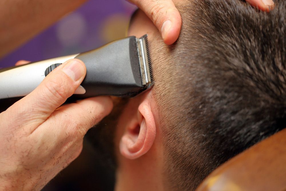 A Man Is Getting His Hair Cut By A Barber With A Clipper —  L'Auranda Hair Salon In  Evan St. Mackay, QLD