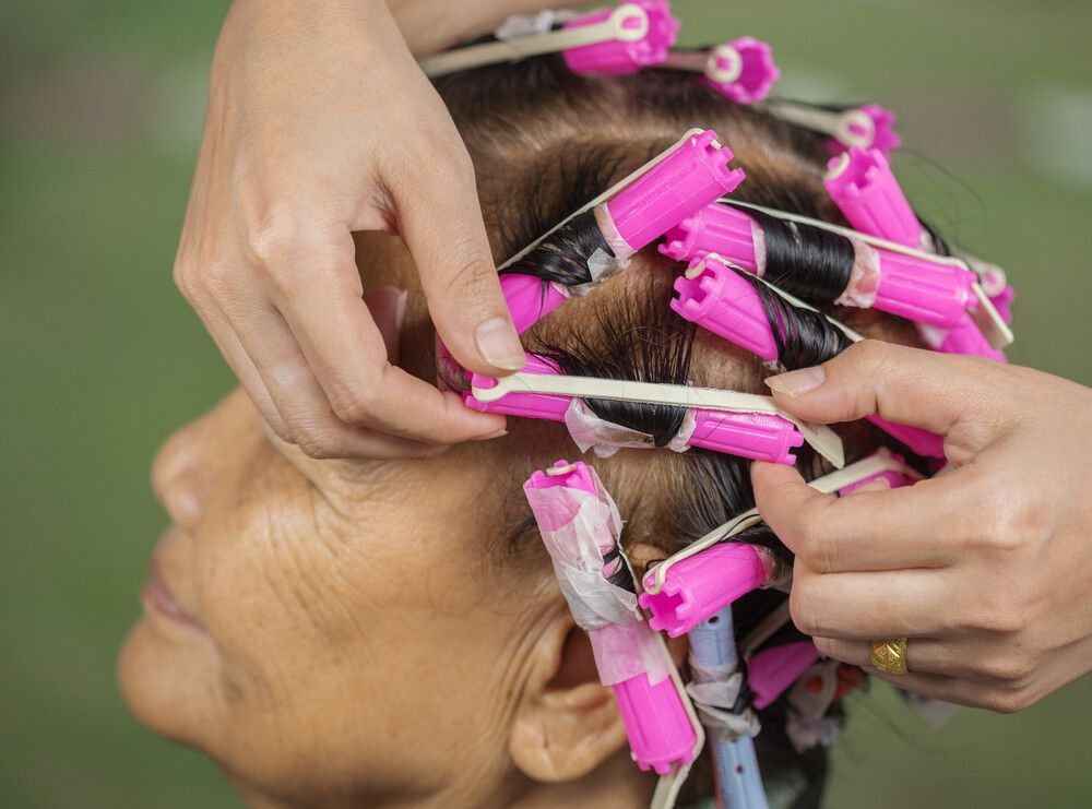 A Woman Is Getting Her Hair Curled With Pink Rollers — L'Auranda Hair Salon In Evan St. Mackay, QLD