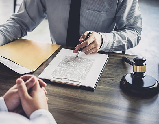 Two men at a desk, reviewing paperwork. A gavel rests nearby.