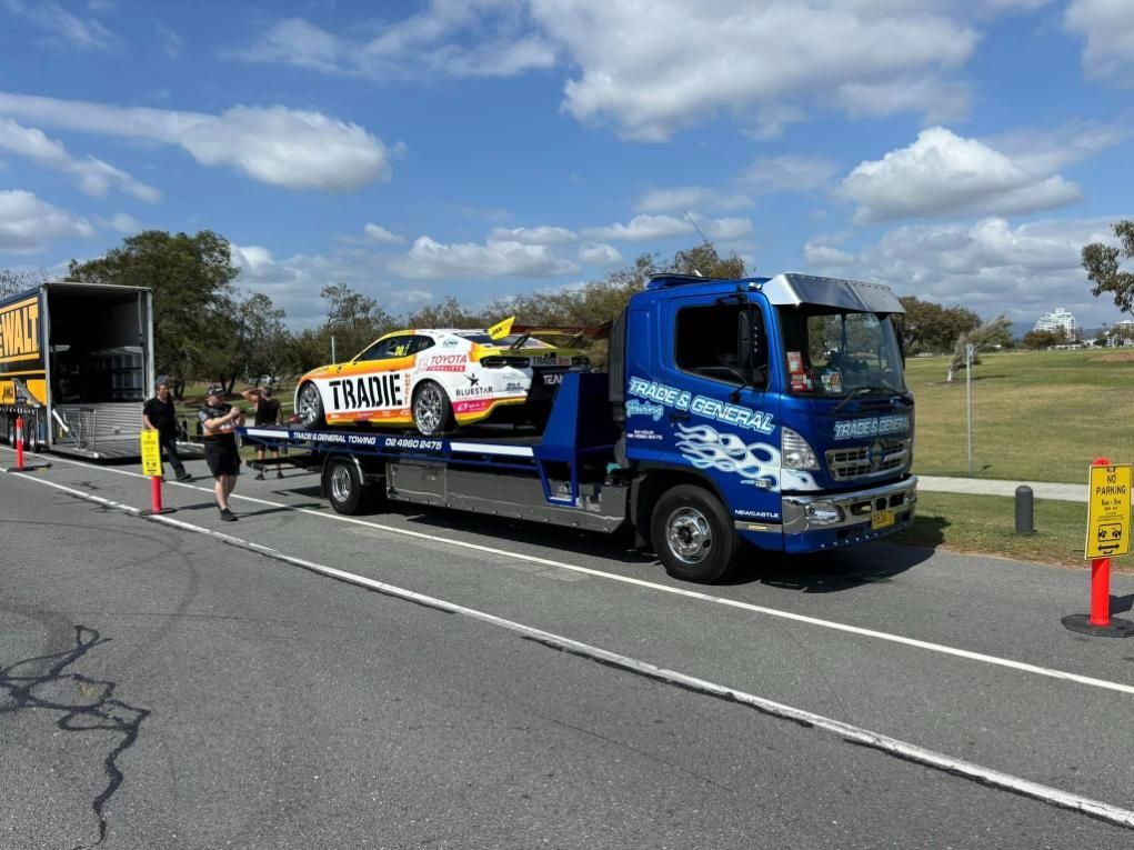 A Tow Truck is Carrying a Race Car Down the Road — Trade & General Towing in Wyong, NSW