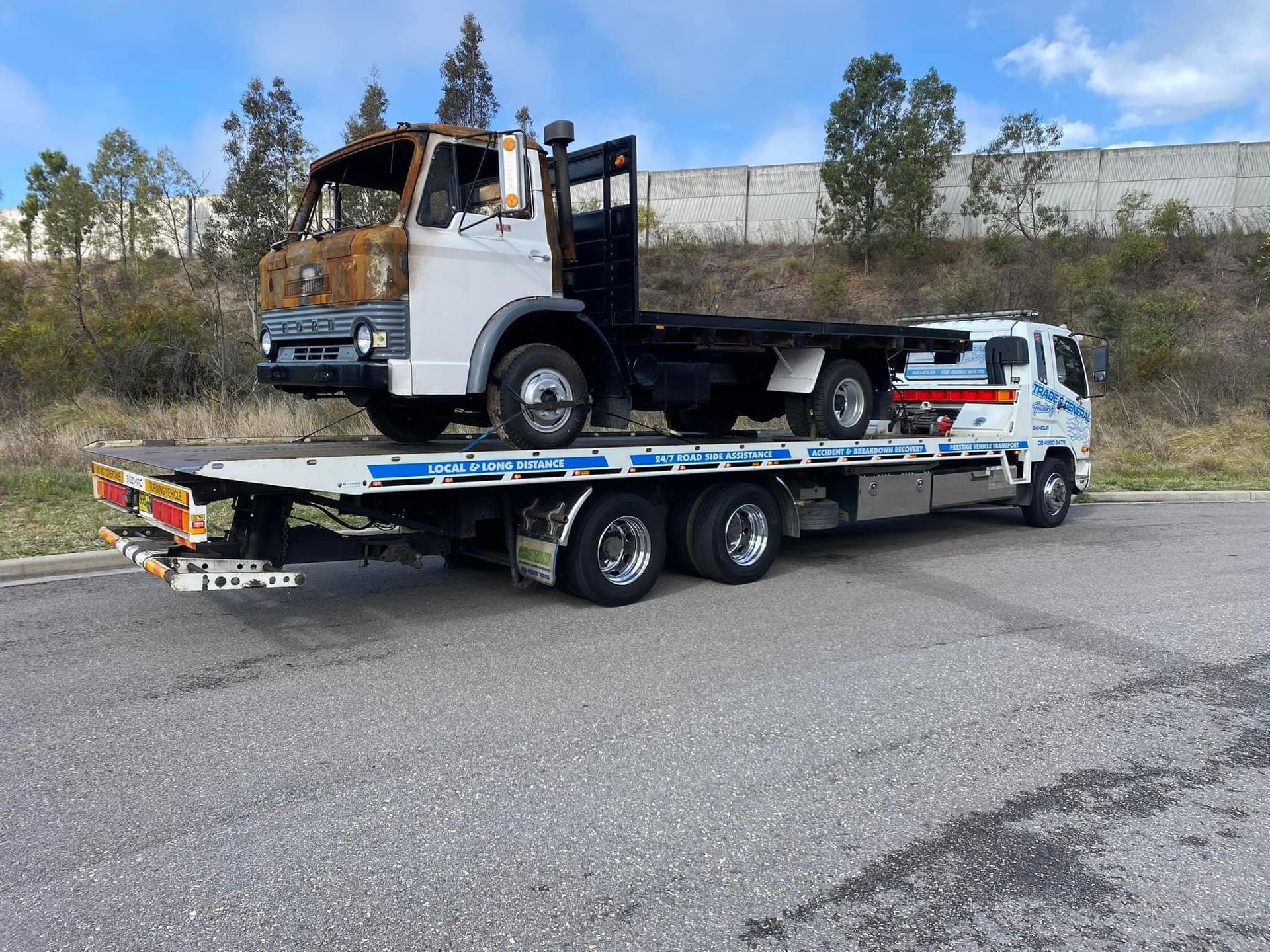 A Tow Truck Carrying A Truck On The Road